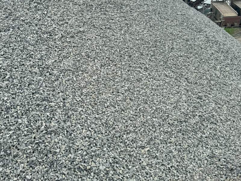 Large stockpile of granite chippings under a conveyor at a quarry