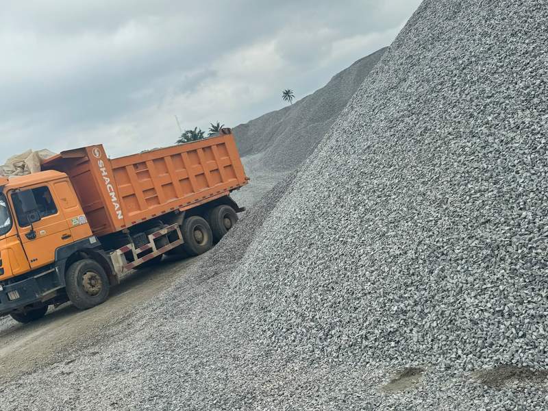 Orange tipper truck beside a stockpile of granite chippings